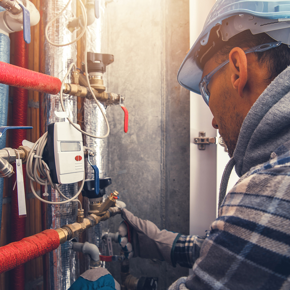 Plumber fixing pipes with safety gear.